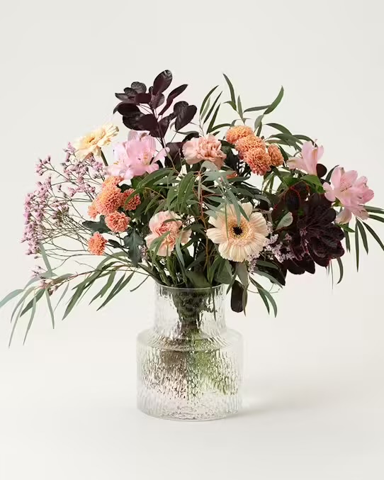 Skicka blommor med bud - beställ hos Interflora! Interfloras vackra oktoberbukett. Den går i pastellfärger som rosa, ljusgult, lätt aprikost och så lite mörk vinrött tillsammans med gröna blad. Blommor: germini, krysantemum, alstroemeria, limonium, perukbuske och dekorationsgrönt